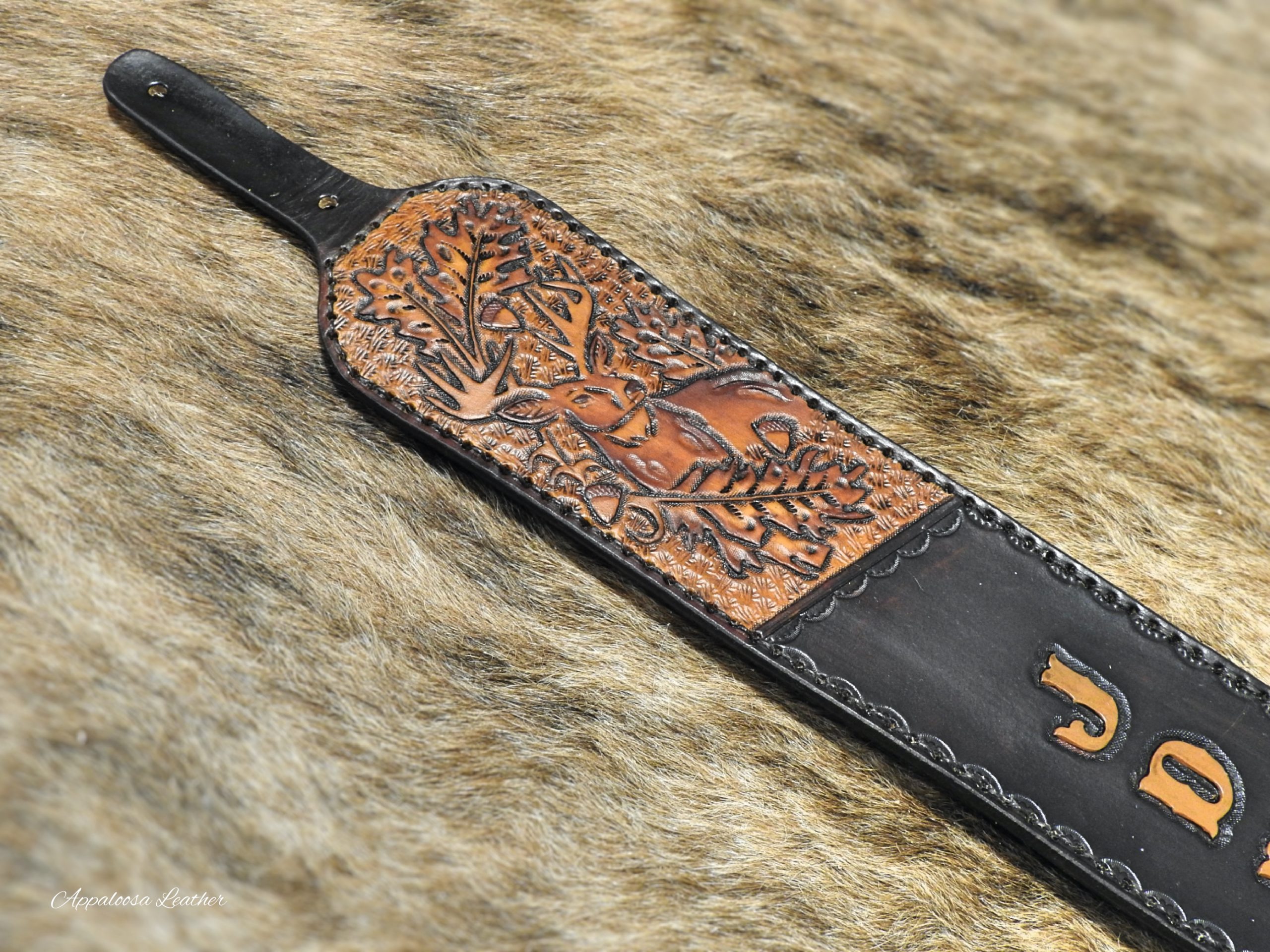 custom leather rifle sling with a whitetail deer, oak leaves and acorn with custom lettering on a dark background